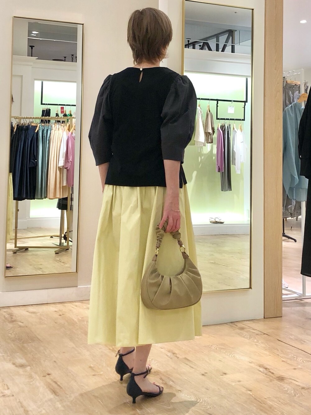 グレー系のTシャツ/カットソー、イエロー系のスカート、ベージュ系のショルダーバッグを着用したレディースの夏コーディネートの5枚目の写真
