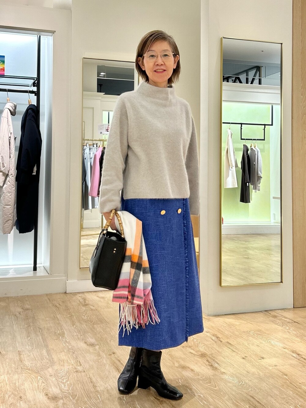 ブルー系のスカート、ブラック系のショルダーバッグ、ベージュ系のニット/セーターを着用したレディースの冬コーディネートの4枚目の写真