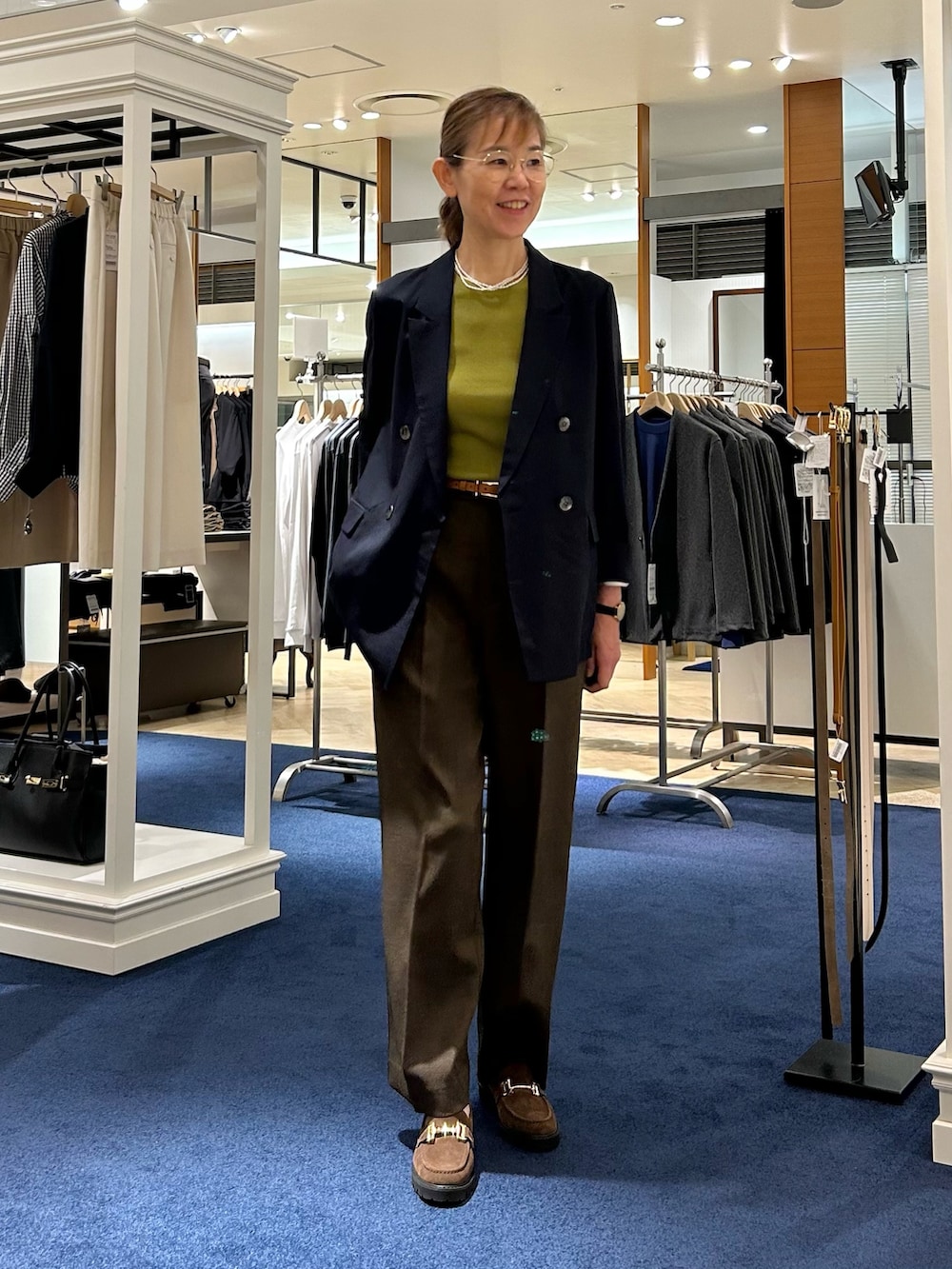 ブラウン系のその他パンツ、ブルー系のテーラードジャケット、グリーン系のニット/セーターを着用したレディースの秋コーディネートの3枚目の写真