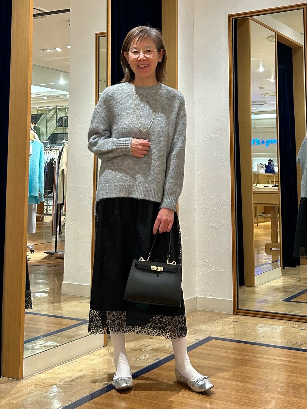 グレー系のニット/セーター、ブラック系のスカート、ブラック系のショルダーバッグを着用したレディースの冬コーディネートの3枚目の写真