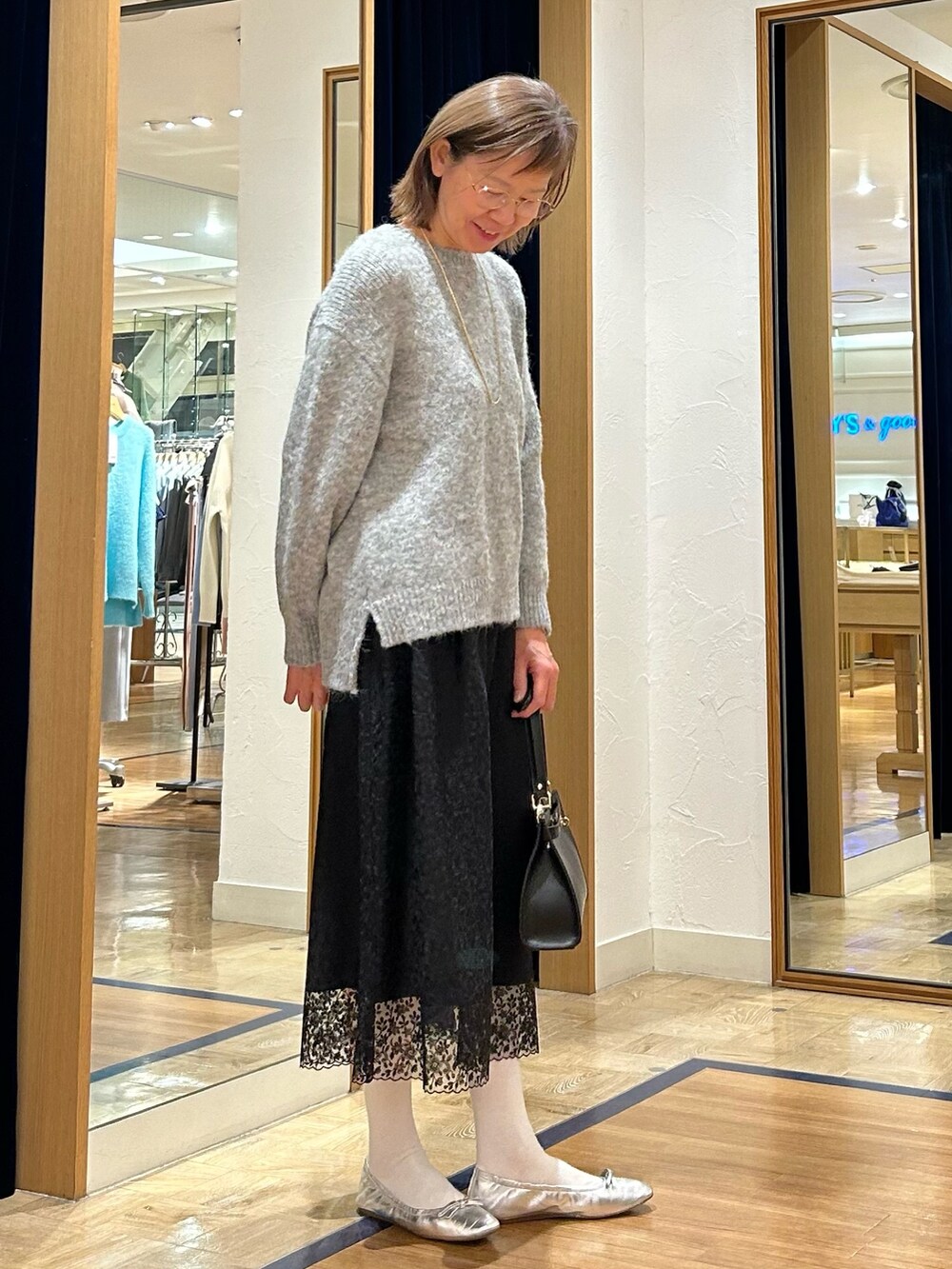 グレー系のニット/セーター、ブラック系のスカート、ブラック系のショルダーバッグを着用したレディースの冬コーディネートの2枚目の写真
