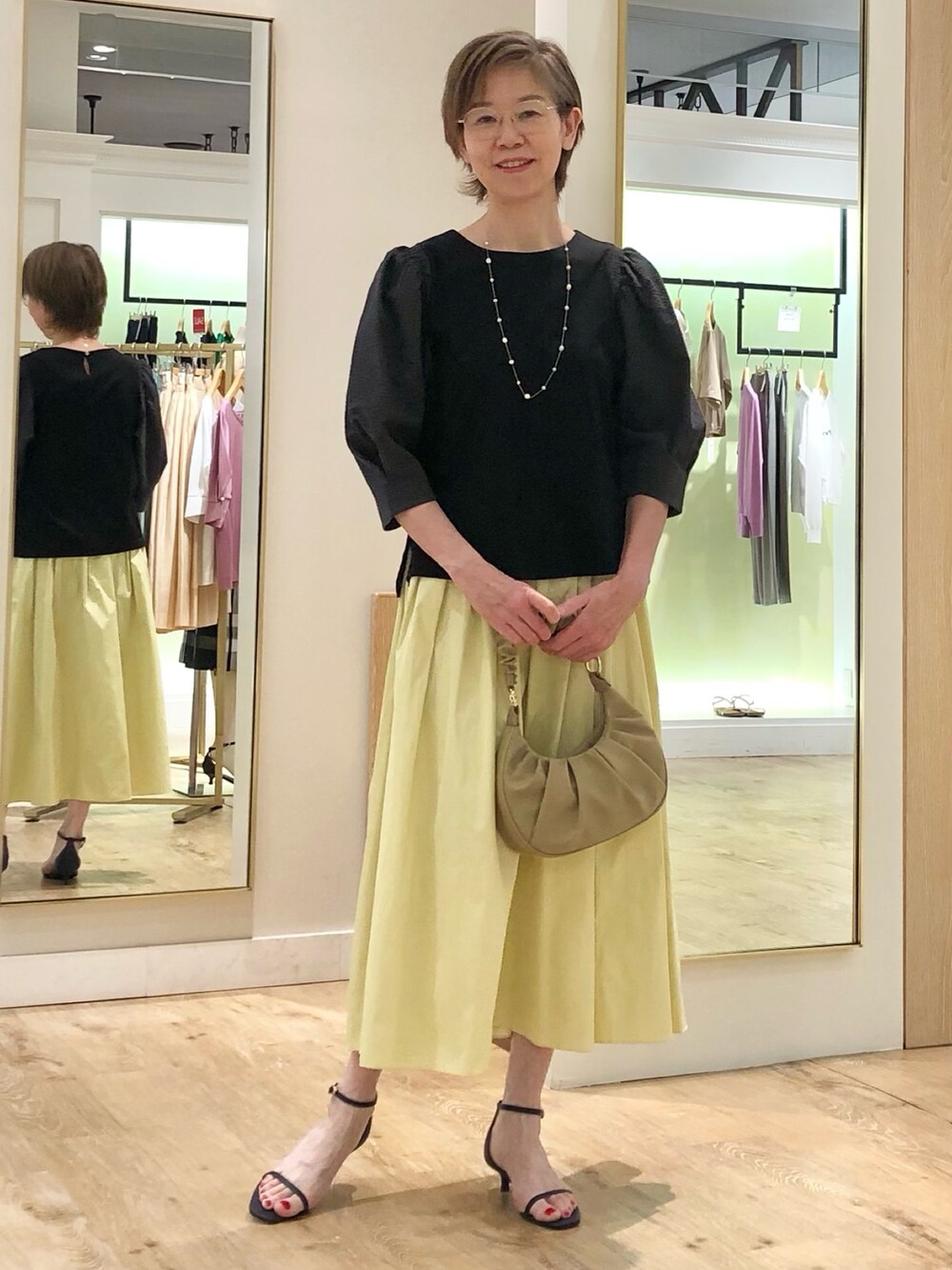 グレー系のTシャツ/カットソー、イエロー系のスカート、ベージュ系のショルダーバッグを着用したレディースの夏コーディネートの2枚目の写真