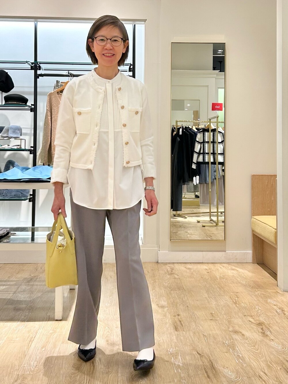 グレー系のその他パンツ、イエロー系のトートバッグ、ホワイト系のカーディガン/ボレロを着用したレディースの冬コーディネートの2枚目の写真