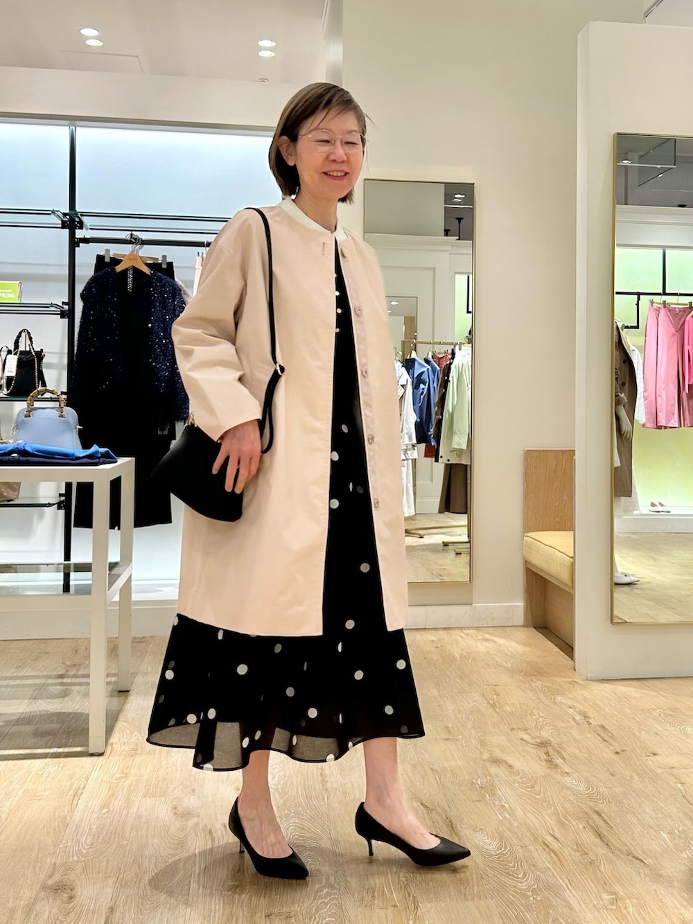 ブルー系のスカート、ピンク系のノーカラーコート、ブラック系のニット/セーターを着用したレディースの春コーディネートの5枚目の写真