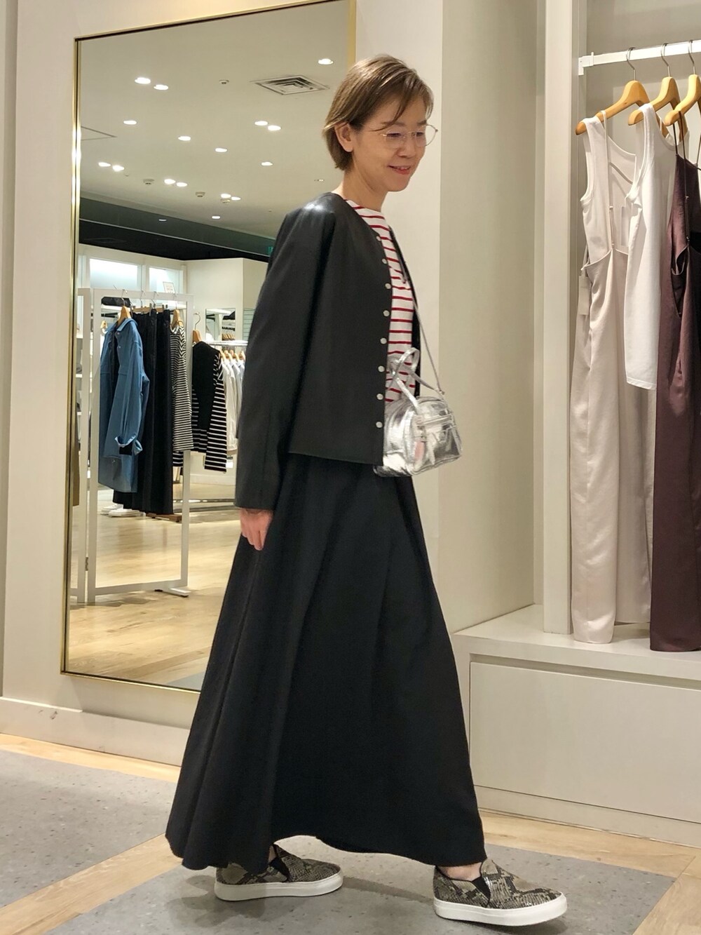 ブラック系のスカート、ブラック系のブルゾン、ホワイト系のTシャツ/カットソーを着用したレディースの夏コーディネートの4枚目の写真