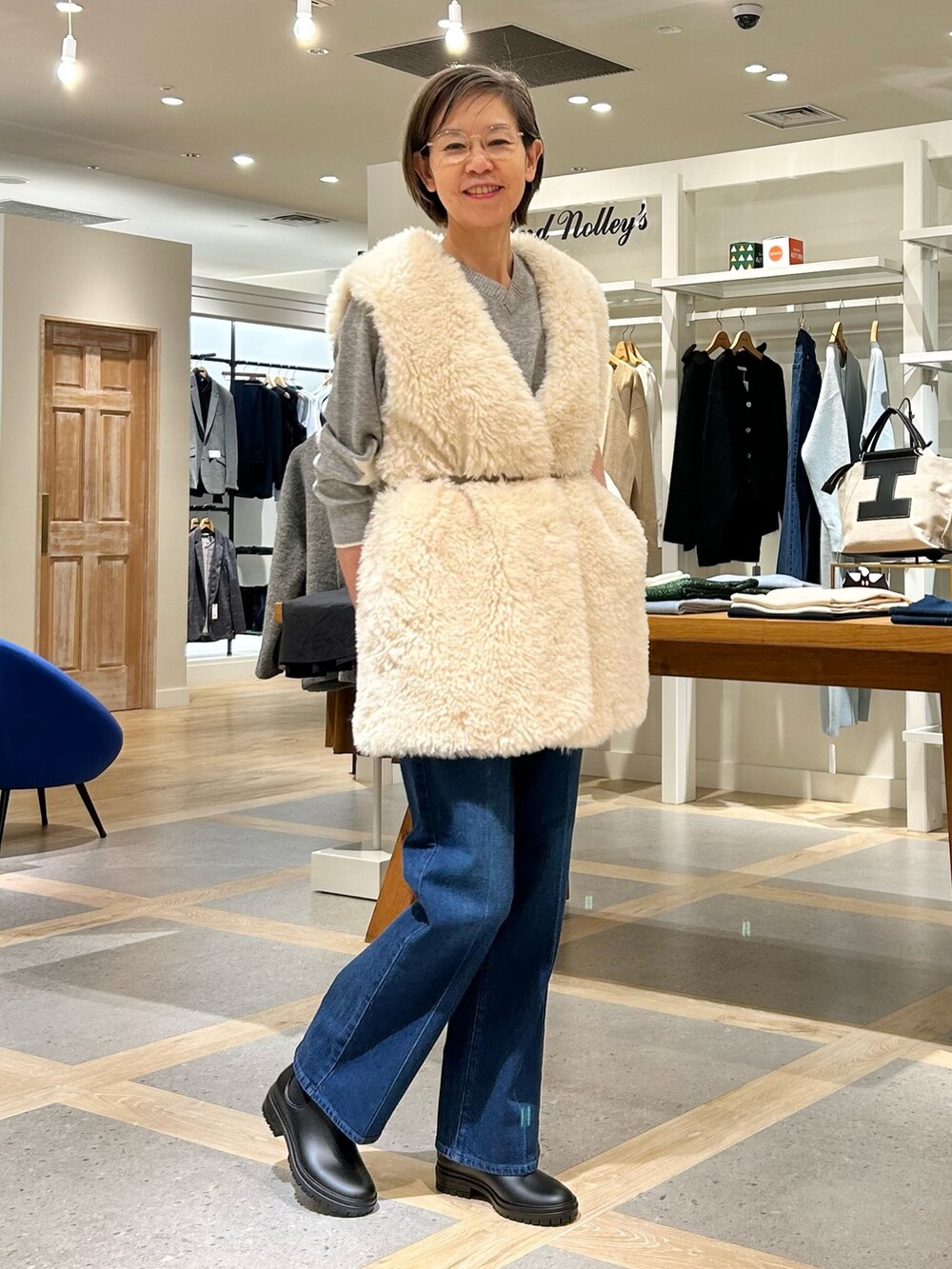 ホワイト系のベスト、グレー系のニット/セーター、ブルー系のデニムパンツを着用したレディースの秋コーディネートの6枚目の写真