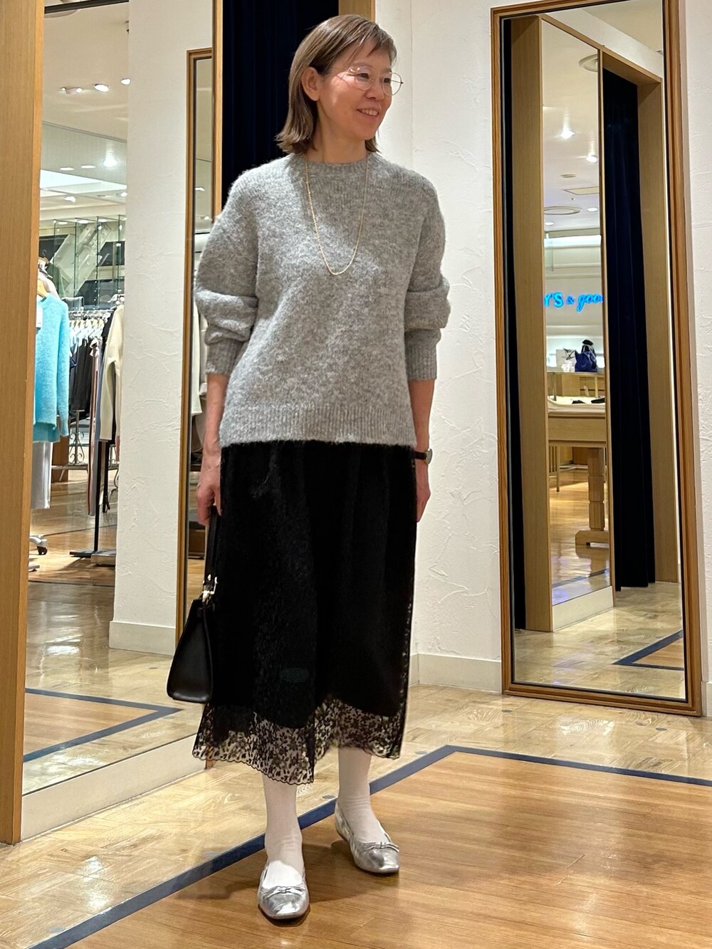グレー系のニット/セーター、ブラック系のスカート、ブラック系のショルダーバッグを着用したレディースの冬コーディネートの4枚目の写真