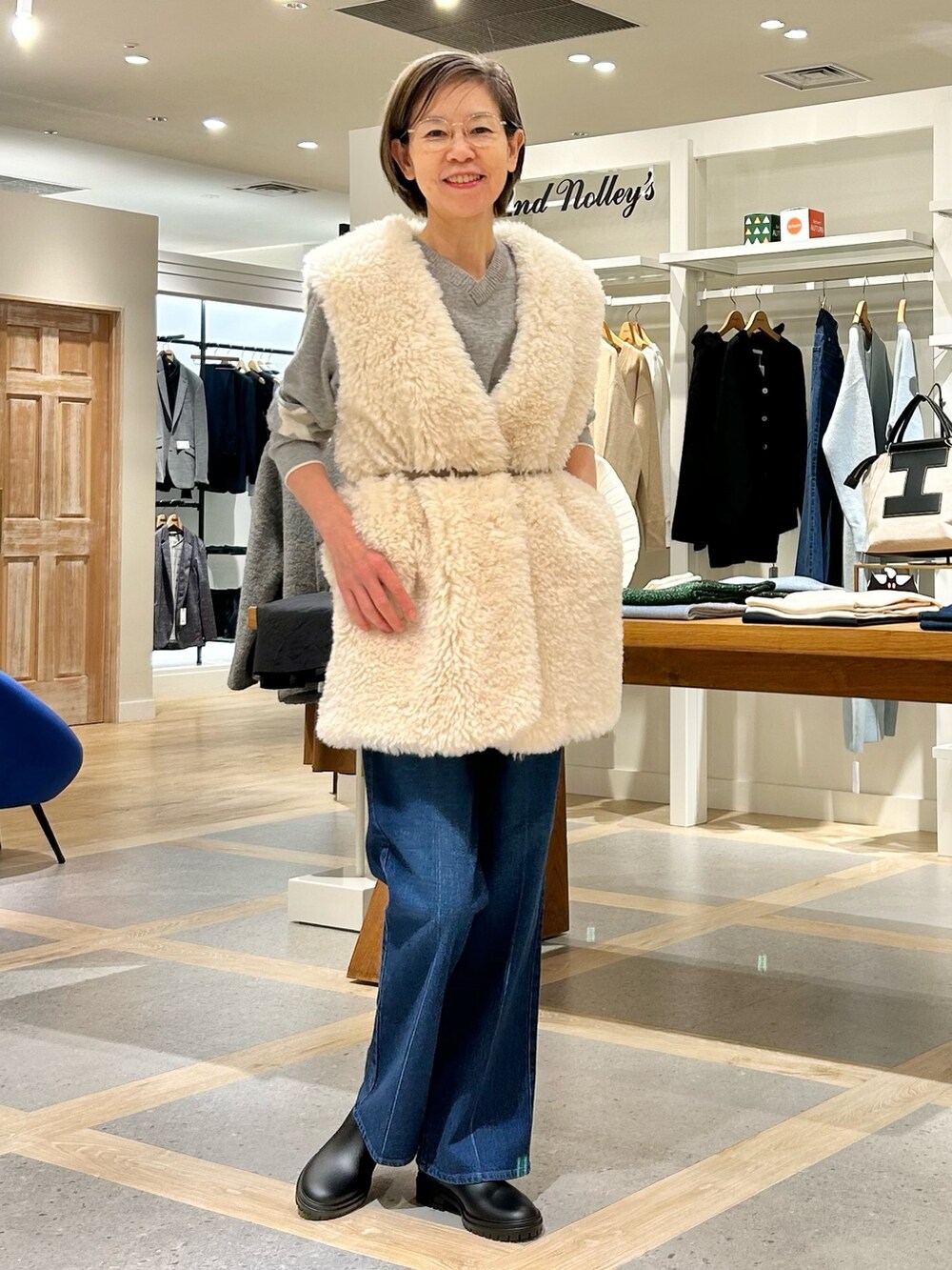 ホワイト系のベスト、グレー系のニット/セーター、ブルー系のデニムパンツを着用したレディースの秋コーディネートの7枚目の写真