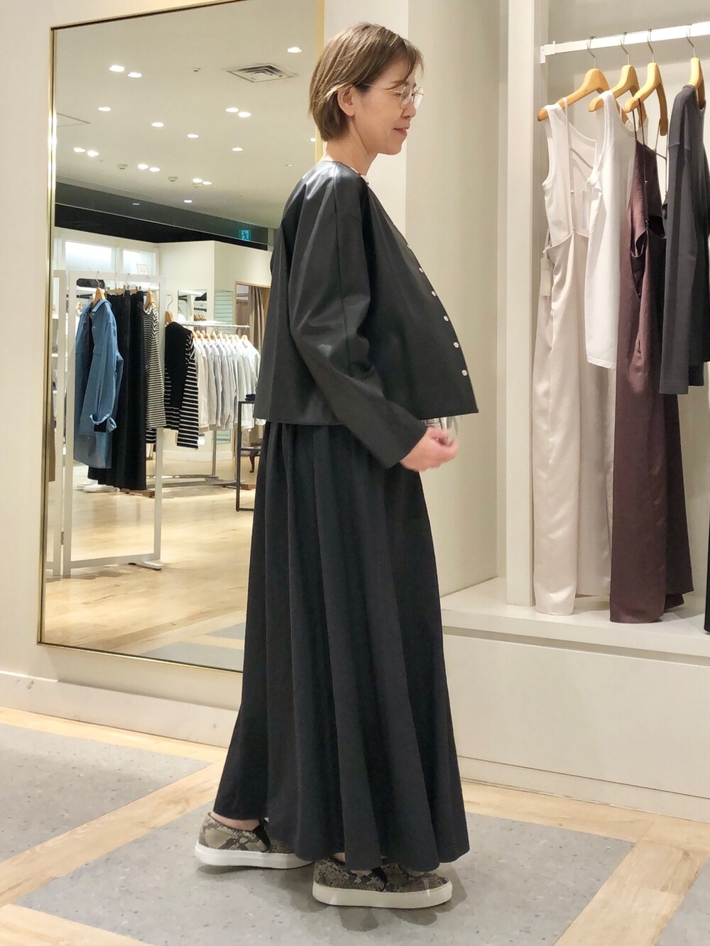 ブラック系のスカート、ブラック系のブルゾン、ホワイト系のTシャツ/カットソーを着用したレディースの夏コーディネートの5枚目の写真