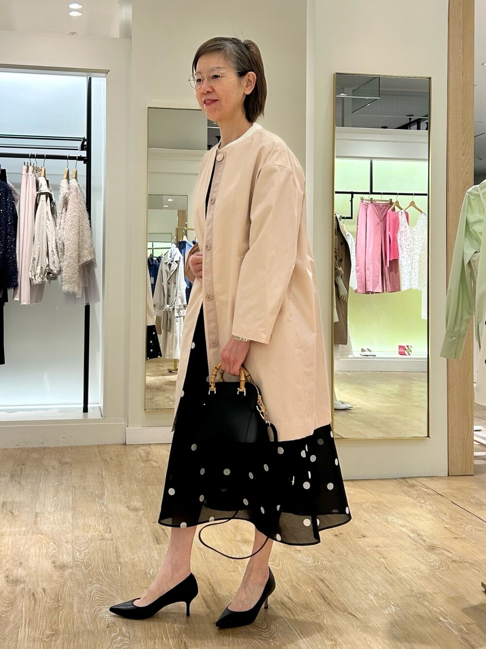 ブルー系のスカート、ピンク系のノーカラーコート、ブラック系のニット/セーターを着用したレディースの春コーディネートの4枚目の写真