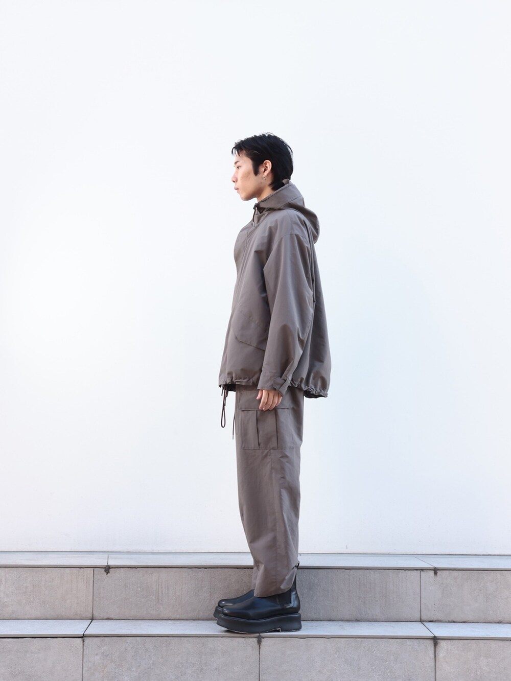 グレー系のカーゴパンツ、ブルー系のニット/セーター、グレー系のブルゾンを着用したメンズの冬コーディネートの3枚目の写真