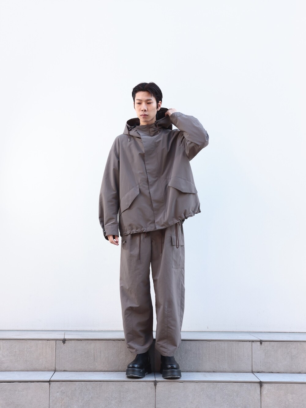 グレー系のカーゴパンツ、ブルー系のニット/セーター、グレー系のブルゾンを着用したメンズの冬コーディネートの2枚目の写真