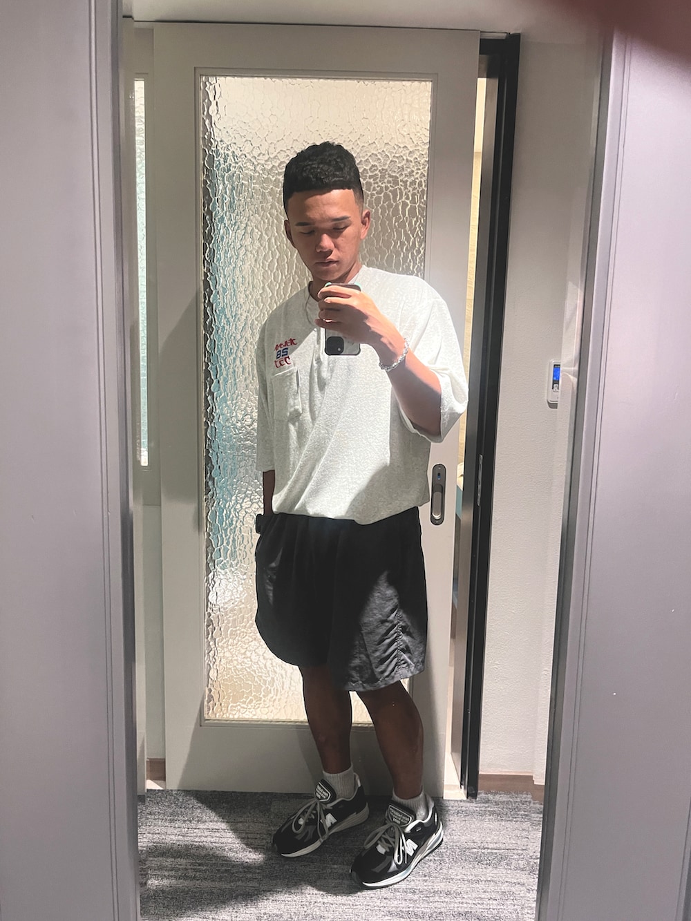 グレー系のパンツ、ホワイト系のトップス、ブラック系のシューズを着用したメンズの夏コーディネートの3枚目の写真