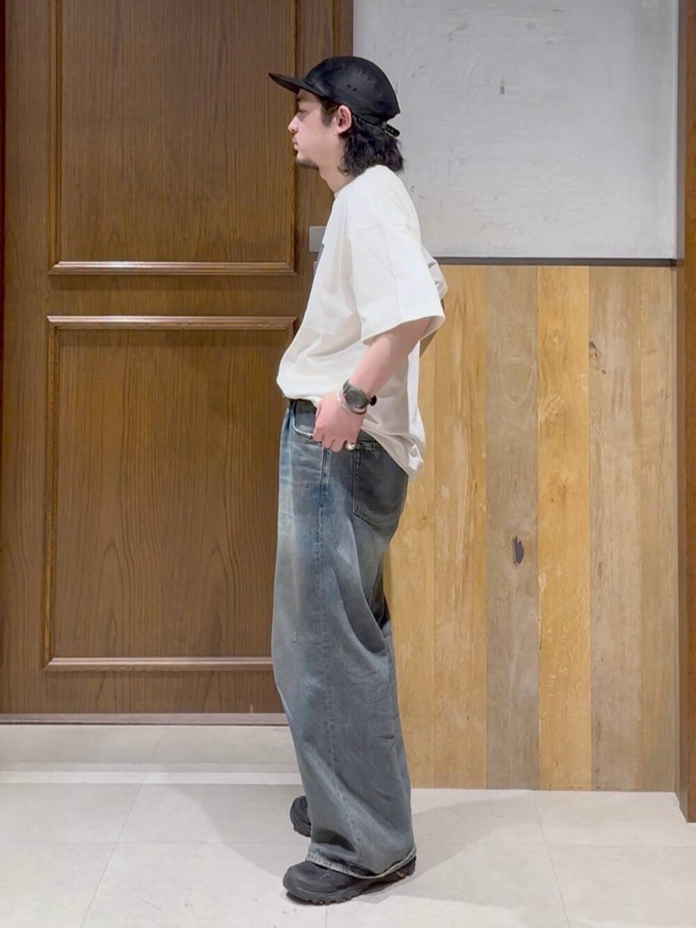 ブルー系のデニムパンツ、ホワイト系のタンクトップ、ブラック系のベルトを着用したメンズの春コーディネートの2枚目の写真