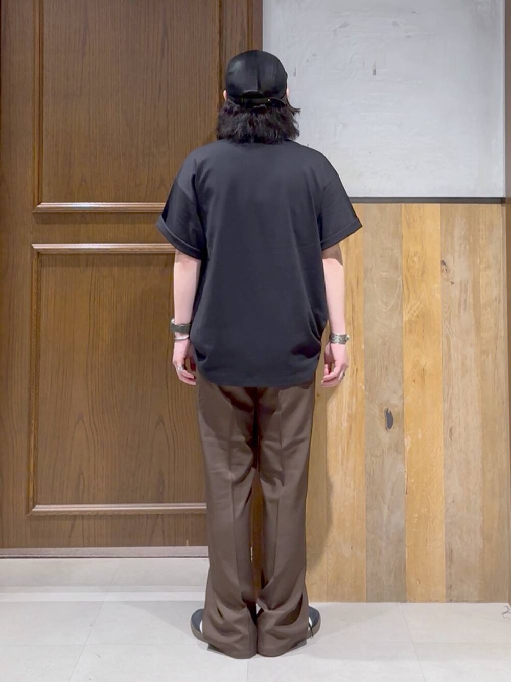 ブラック系のスニーカー、ブラック系のTシャツ/カットソー、ブラウン系のスラックスを着用したメンズの夏コーディネートの2枚目の写真