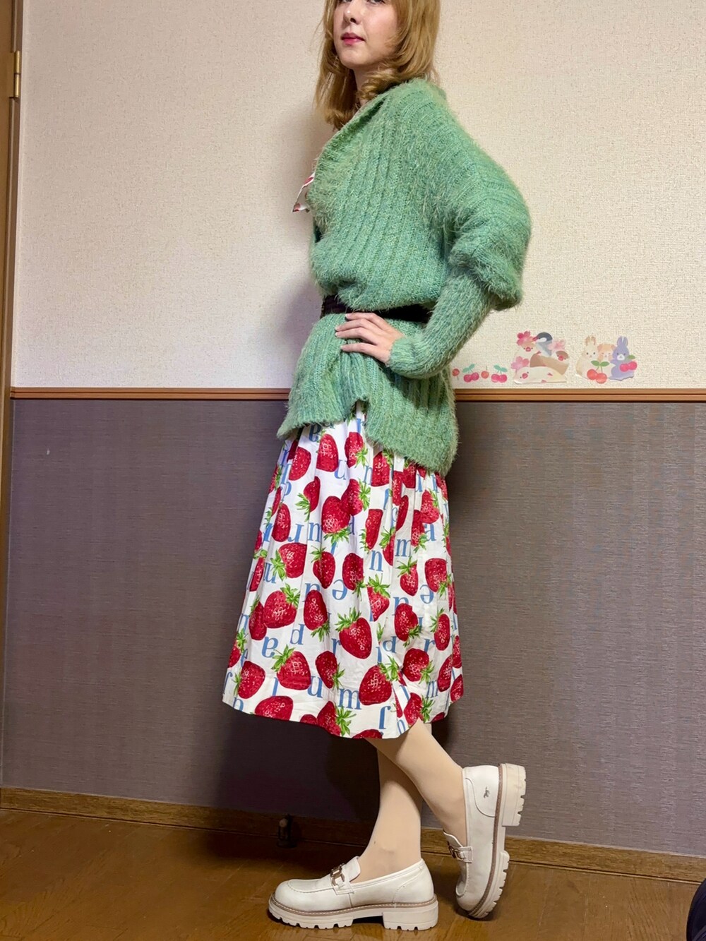グリーン系のニット/セーター、ホワイト系のスカート、ホワイト系のシューズを着用したレディースの秋コーディネートの4枚目の写真