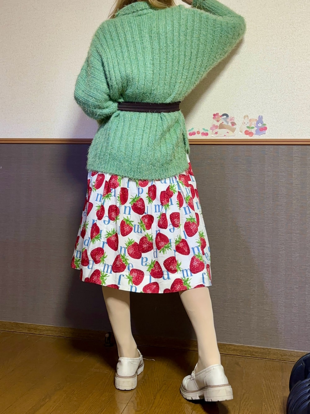 グリーン系のニット/セーター、ホワイト系のスカート、ホワイト系のシューズを着用したレディースの秋コーディネートの2枚目の写真