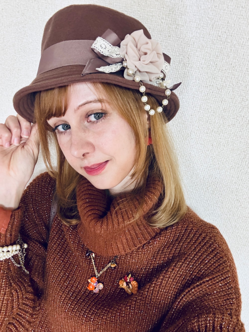 オレンジ系のニット/セーター、ブラウン系のバッグ、ブラウン系のスカートを着用したレディースの冬コーディネートの5枚目の写真