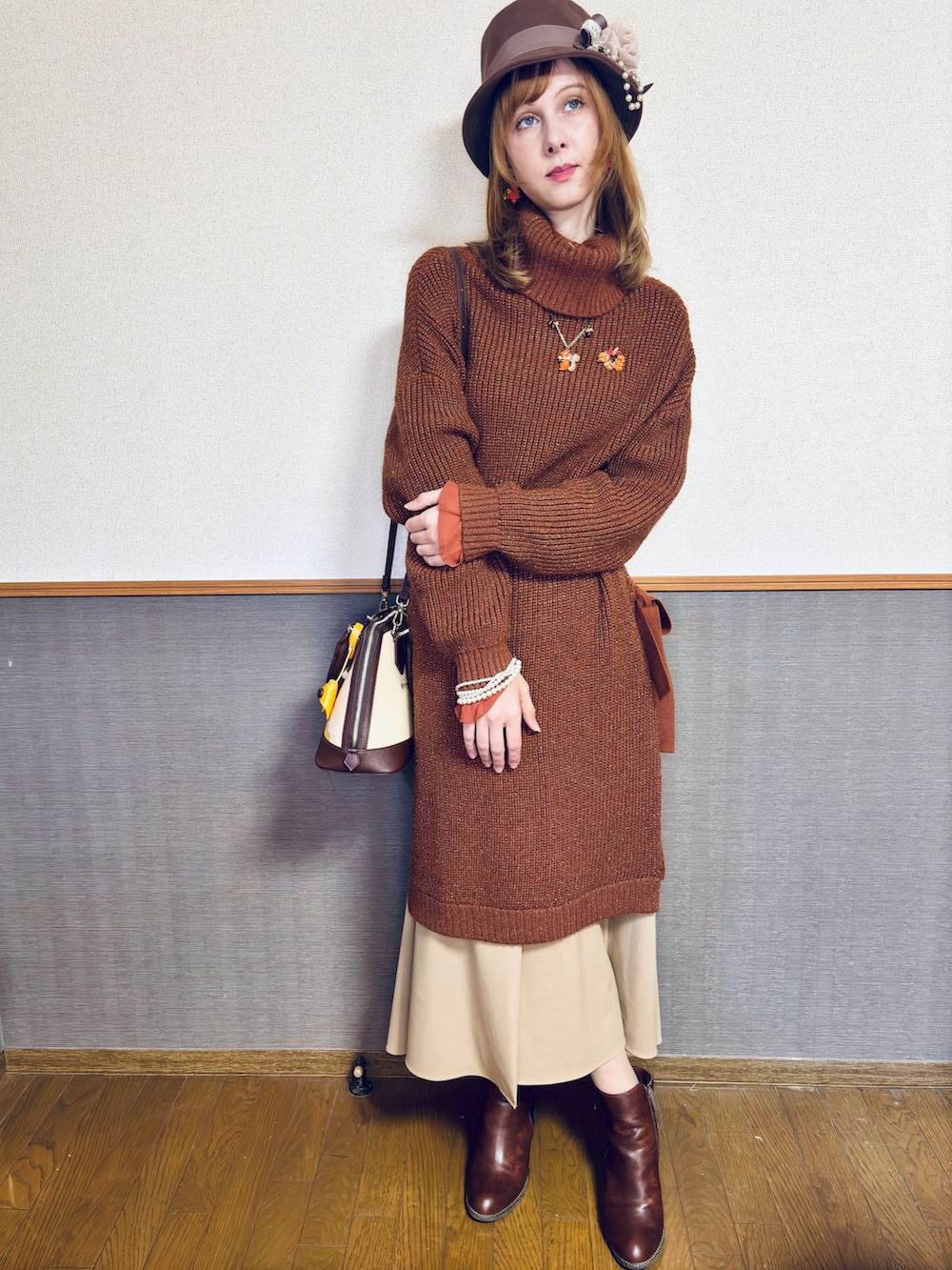 オレンジ系のニット/セーター、ブラウン系のバッグ、ブラウン系のスカートを着用したレディースの冬コーディネートの2枚目の写真