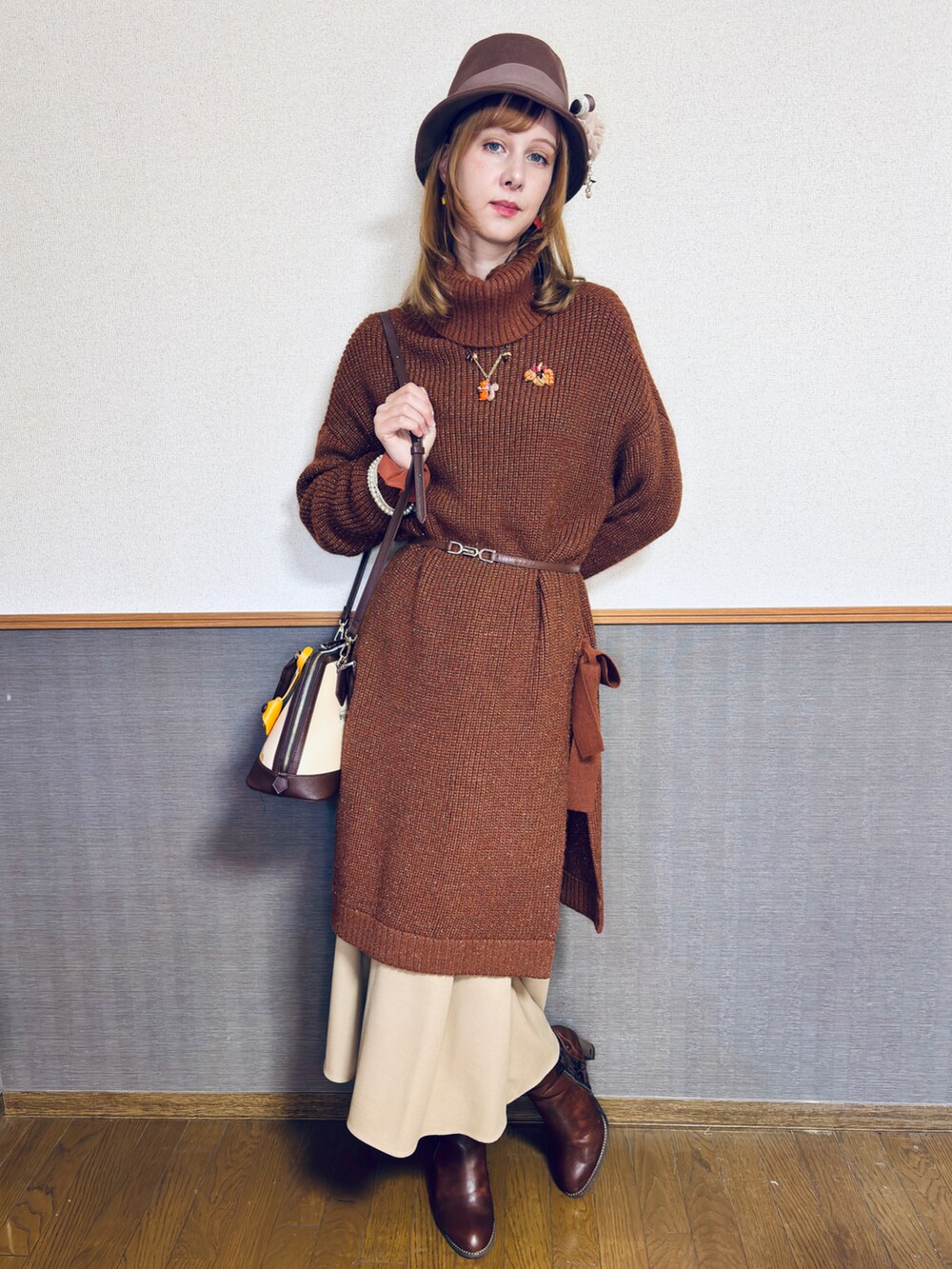 オレンジ系のニット/セーター、ブラウン系のバッグ、ブラウン系のスカートを着用したレディースの冬コーディネートの3枚目の写真