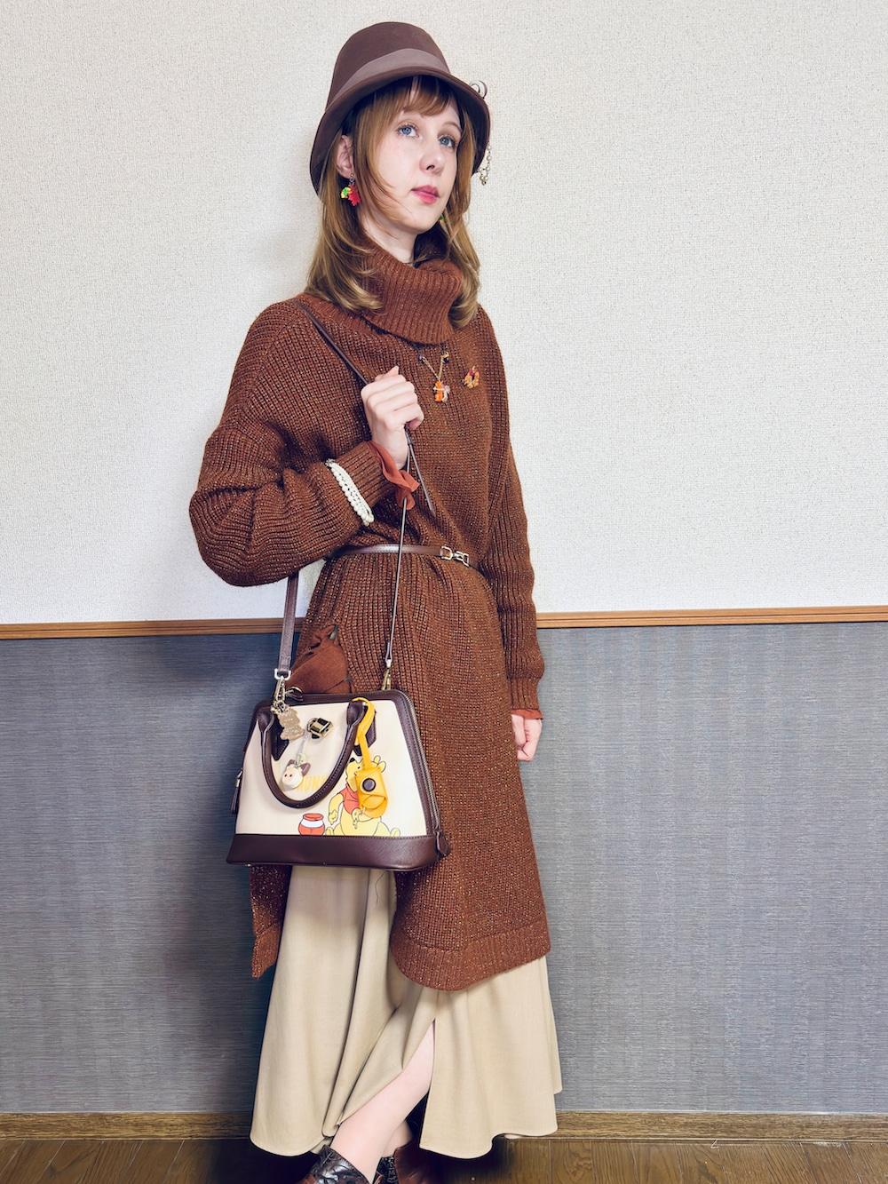 オレンジ系のニット/セーター、ブラウン系のバッグ、ブラウン系のスカートを着用したレディースの冬コーディネートの4枚目の写真