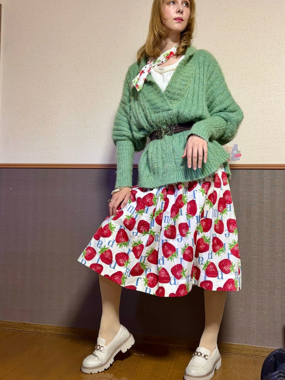 グリーン系のニット/セーター、ホワイト系のスカート、ホワイト系のシューズを着用したレディースの秋コーディネートの3枚目の写真