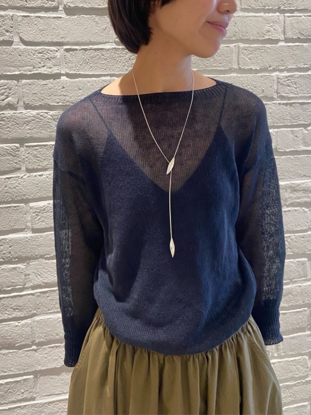 グリーン系のスカート、ブルー系のニット/セーターを着用したレディースの夏コーディネートの2枚目の写真