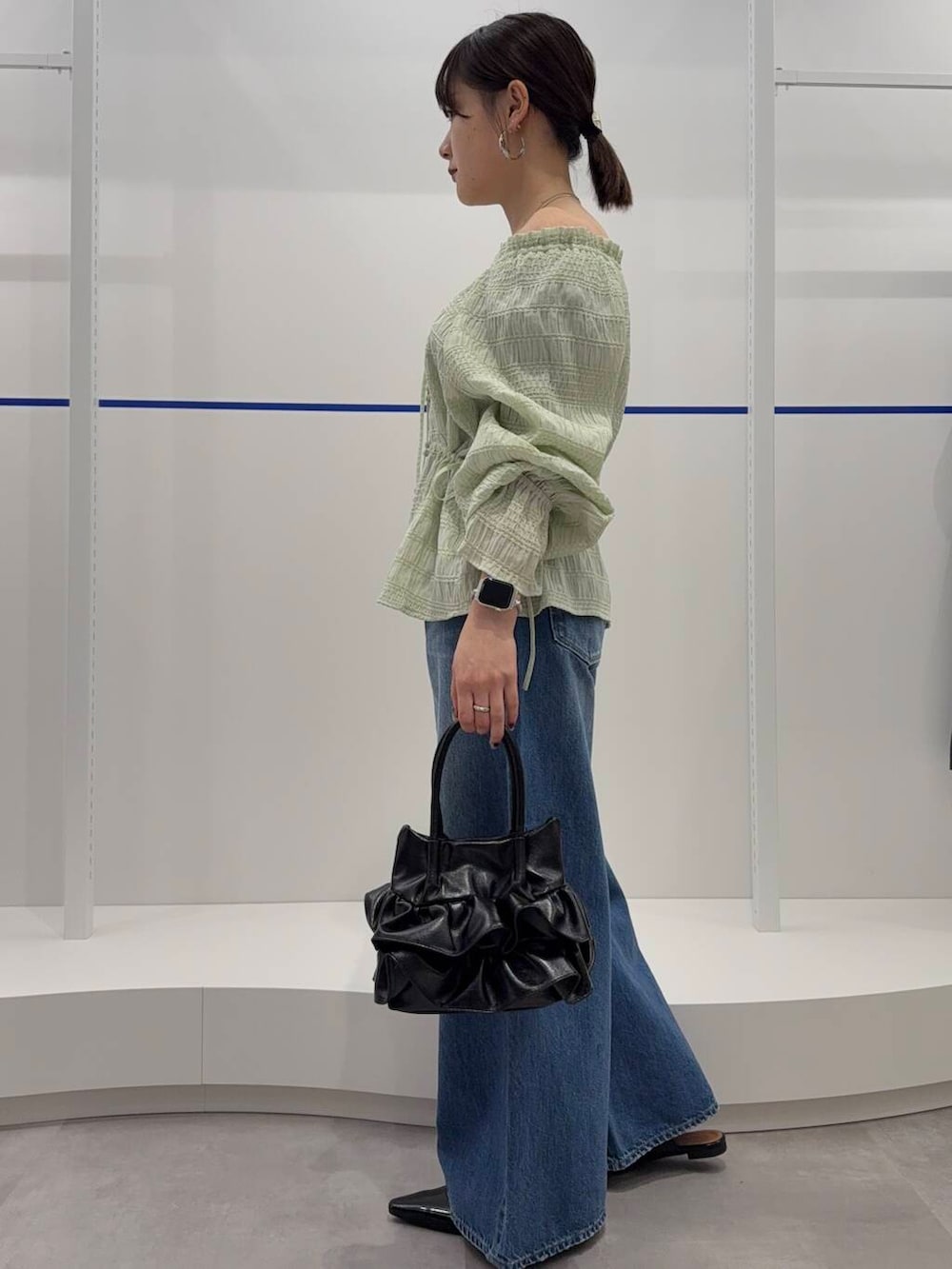 ブルー系のデニムパンツ、ブラック系のパンプス、グリーン系のシャツ/ブラウスを着用したレディースの春コーディネートの2枚目の写真