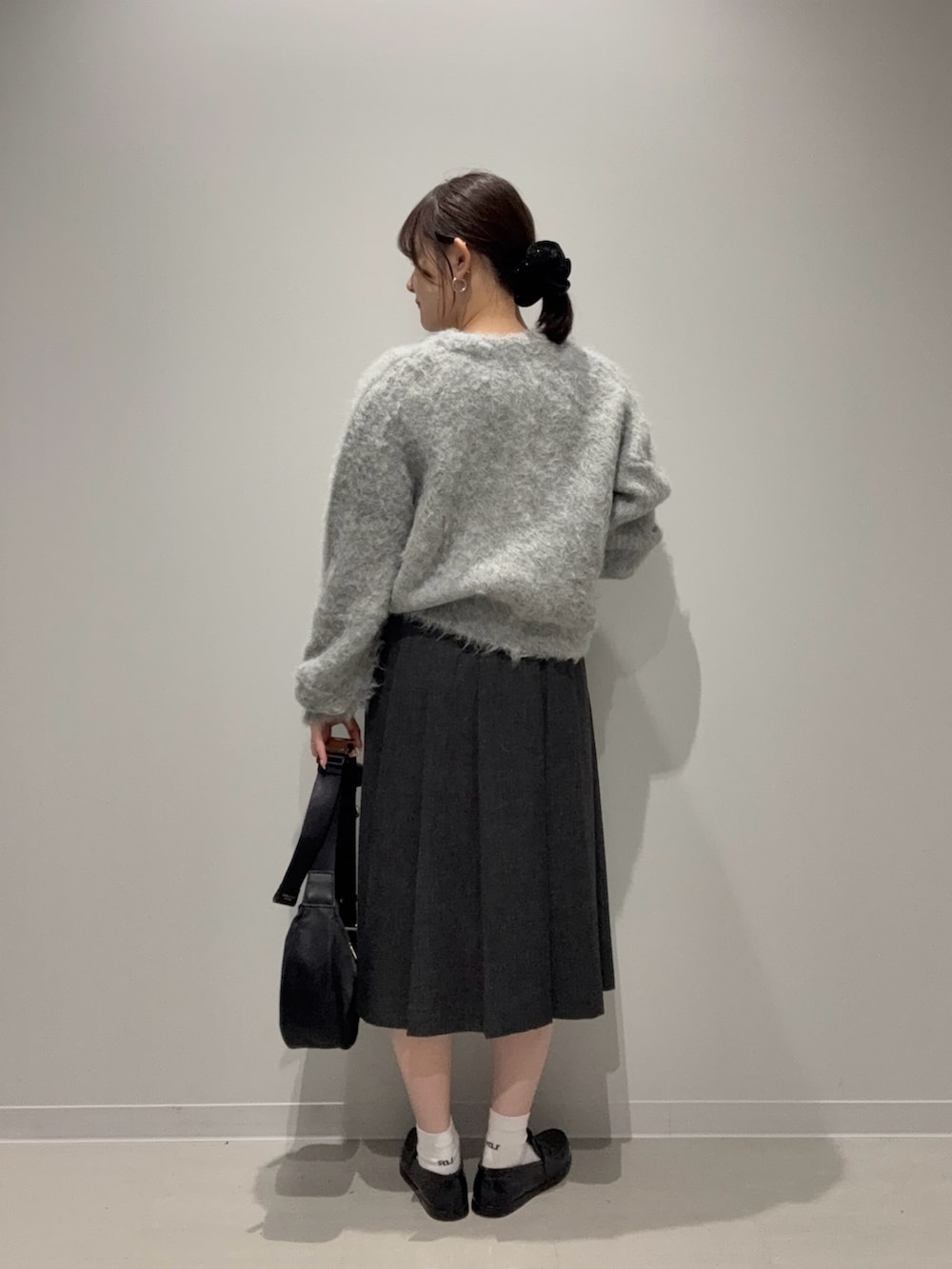 グレー系のスカート、グレー系のカーディガン/ボレロ、ブラック系のショルダーバッグを着用したレディースの秋コーディネートの3枚目の写真