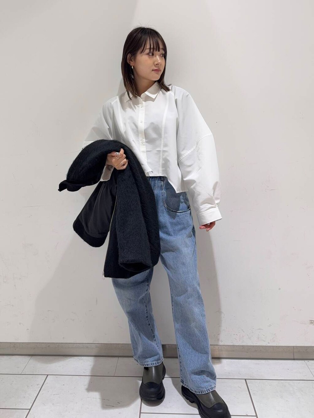ブルー系のデニムパンツ、ブラック系のボストンバッグ、グリーン系のブーツを着用したレディースの冬コーディネートの2枚目の写真