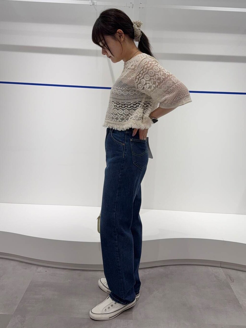 ホワイト系のショルダーバッグ、ホワイト系のスニーカー、ブルー系のデニムパンツを着用したレディースの春コーディネートの2枚目の写真