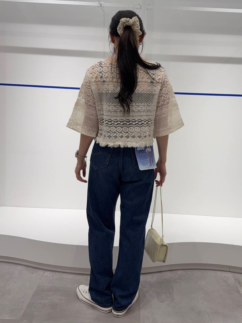 ホワイト系のショルダーバッグ、ホワイト系のスニーカー、ブルー系のデニムパンツを着用したレディースの春コーディネートの3枚目の写真