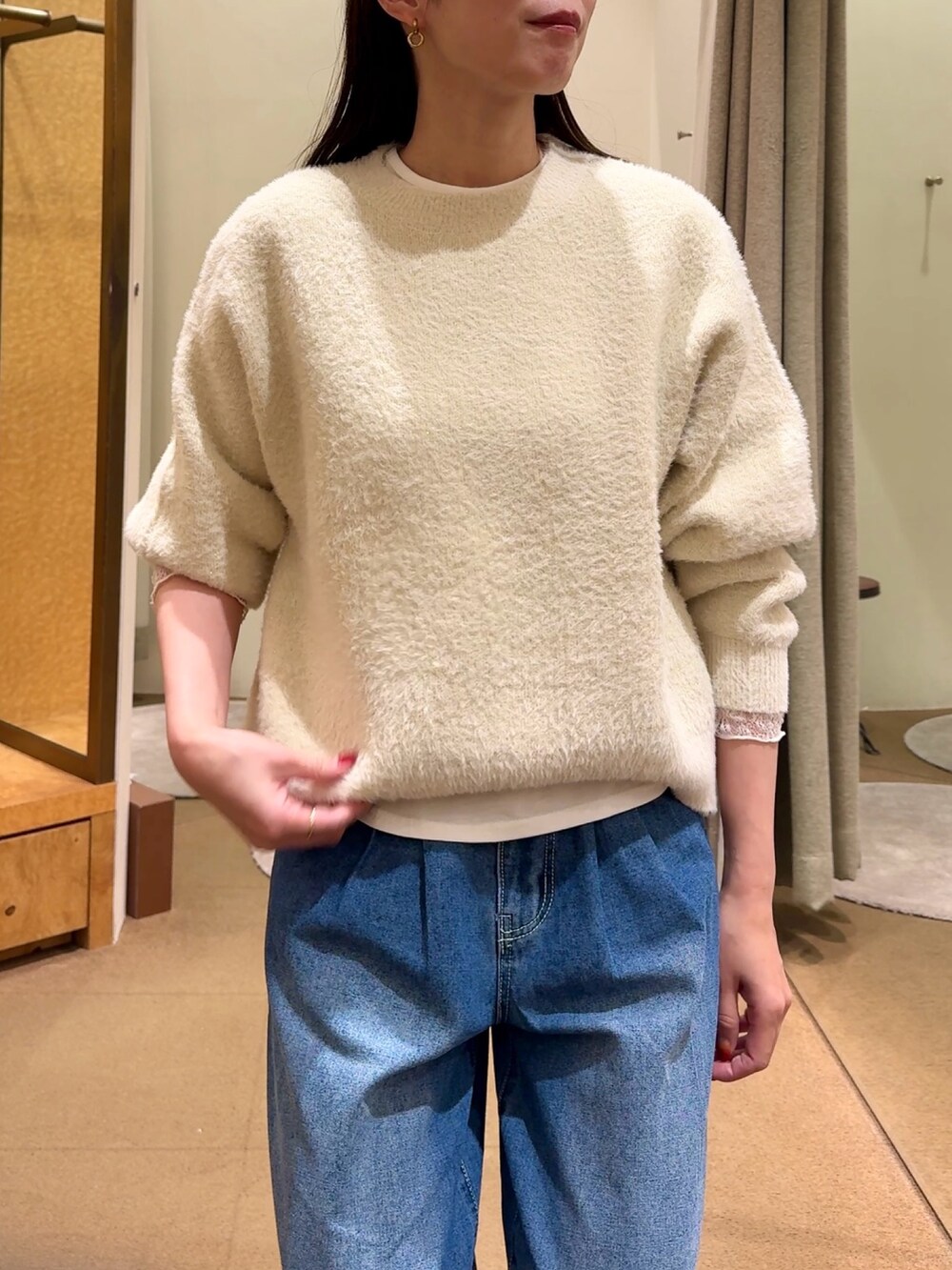 ホワイト系のニット/セーター、ホワイト系のTシャツ/カットソー、ブルー系のデニムパンツを着用したレディースの冬コーディネートの3枚目の写真