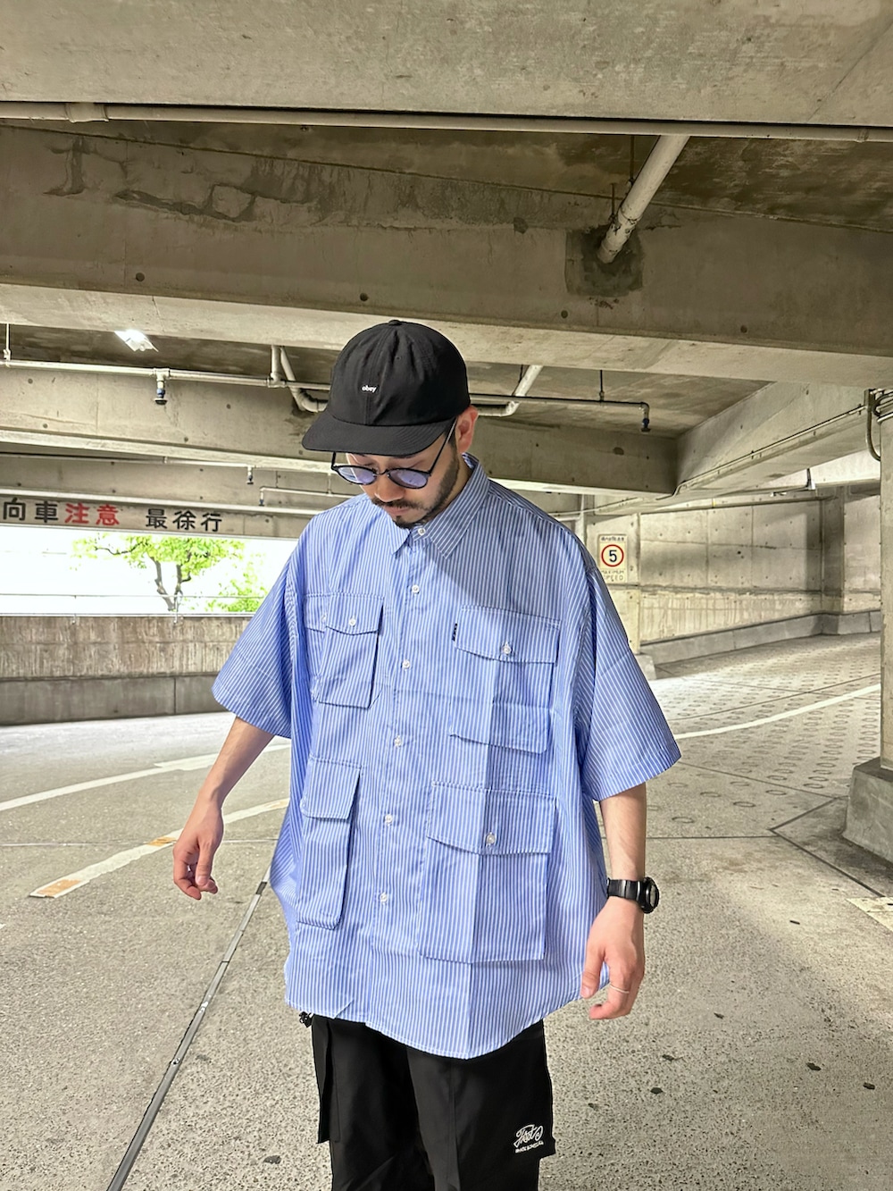 ブルー系のシャツ/ブラウス、ブラック系のカーゴパンツ、グレー系のスニーカーを着用したメンズの春コーディネートの2枚目の写真