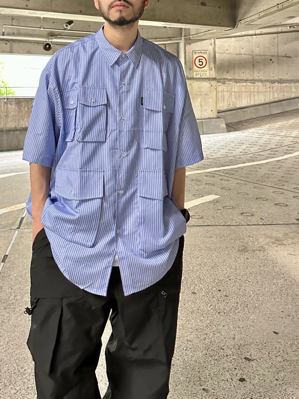 ブルー系のシャツ/ブラウス、ブラック系のカーゴパンツ、グレー系のスニーカーを着用したメンズの春コーディネートの3枚目の写真