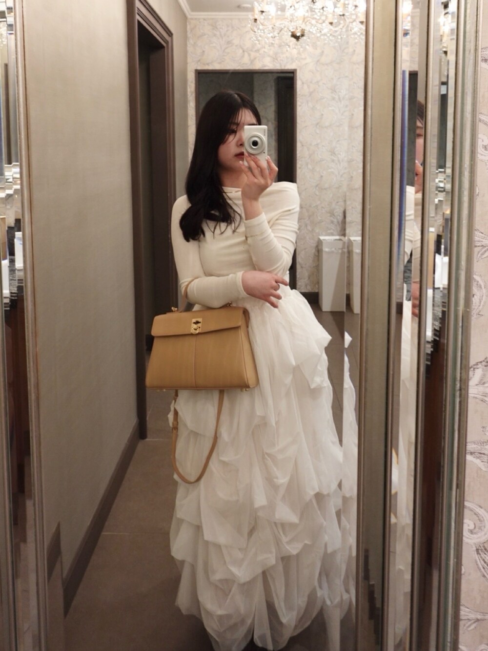 ホワイト系のスカート、ブラウン系のブーツ、ベージュ系のハンドバッグを着用したレディースの春コーディネートの3枚目の写真