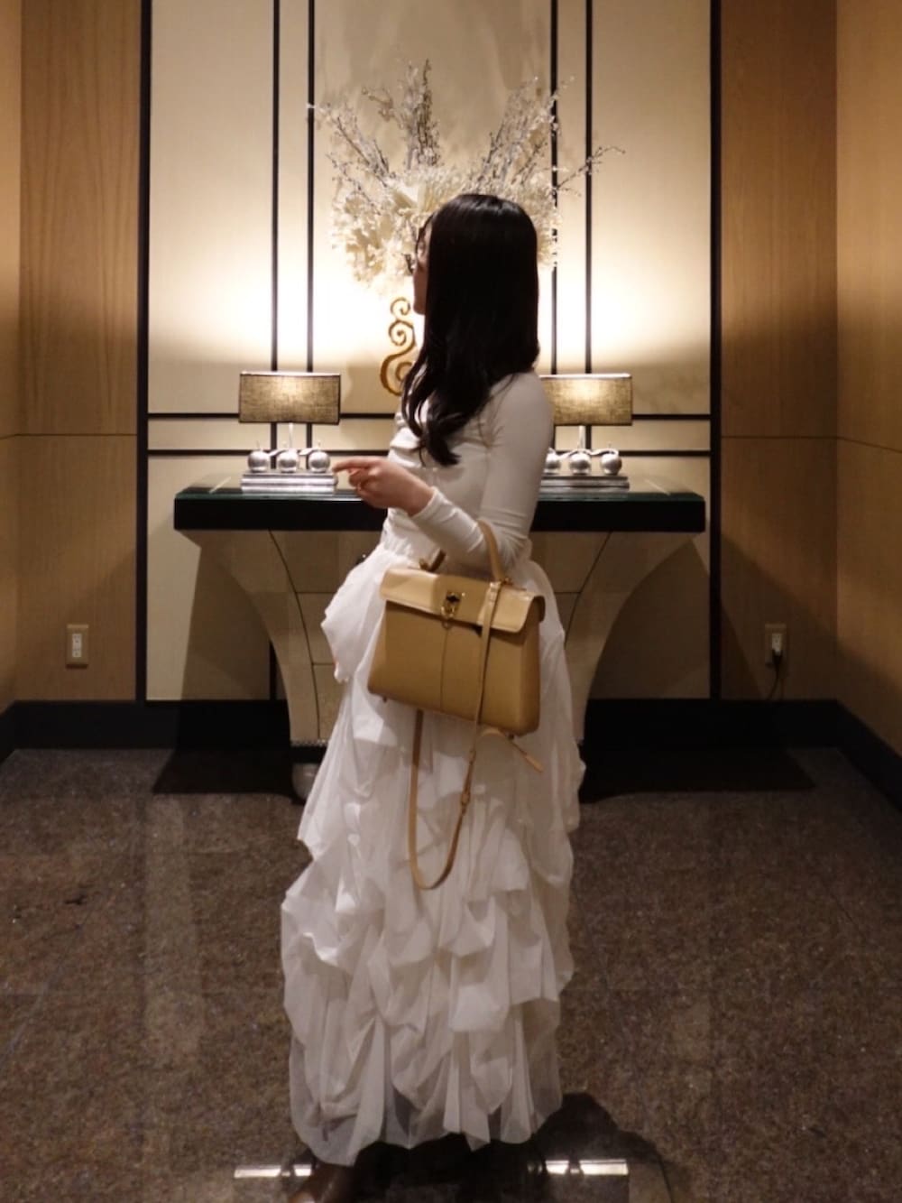 ホワイト系のスカート、ブラウン系のブーツ、ベージュ系のハンドバッグを着用したレディースの春コーディネートの2枚目の写真