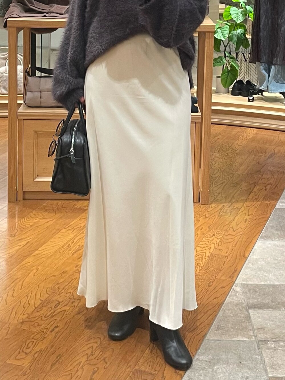 グレー系のニット/セーター、ホワイト系のスカート、ブラック系のブーツを着用したレディースの秋コーディネートの3枚目の写真