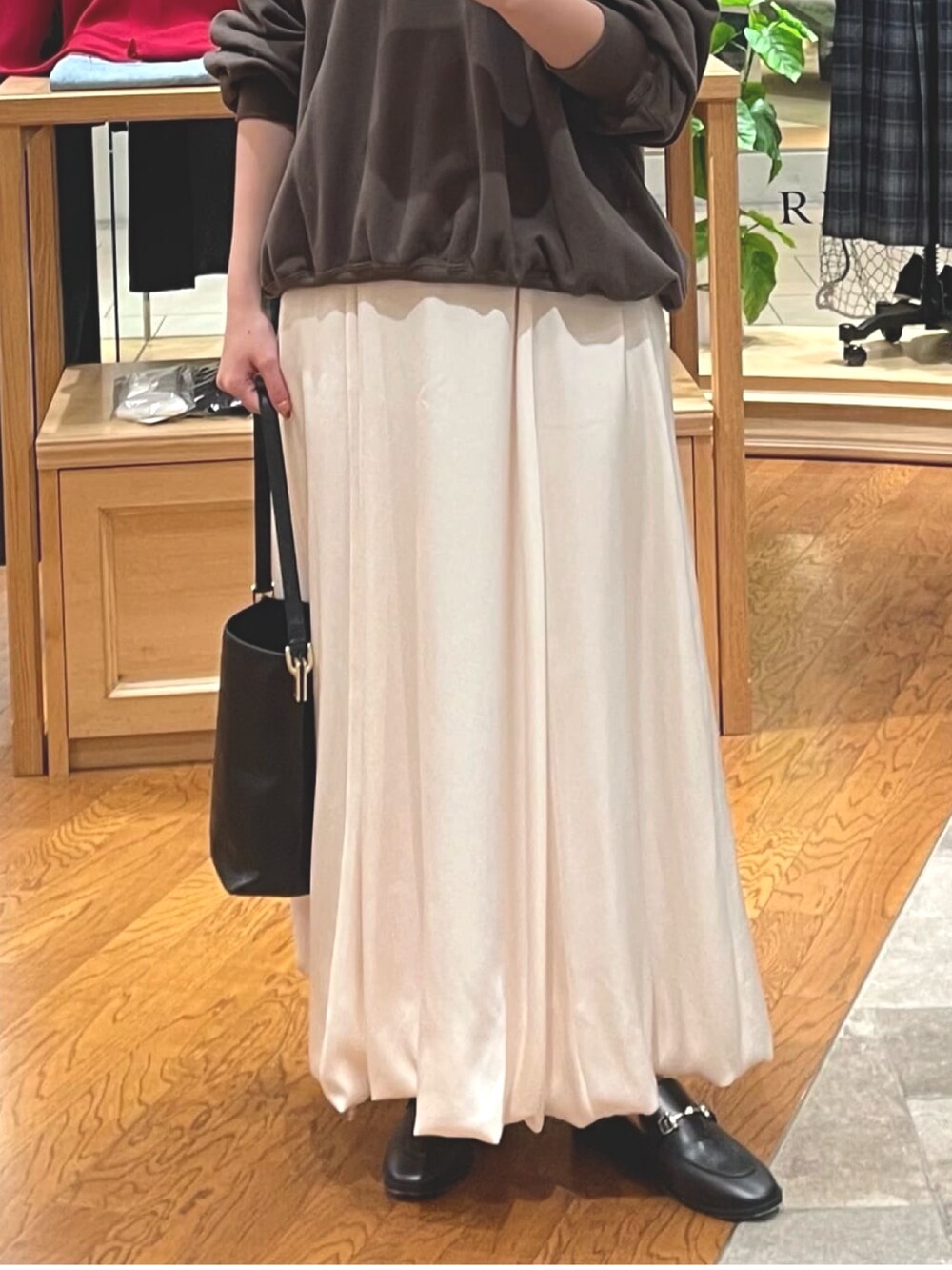 ブラウン系のスウェット、ホワイト系のスカート、ブラック系のローファーを着用したレディースの秋コーディネートの3枚目の写真