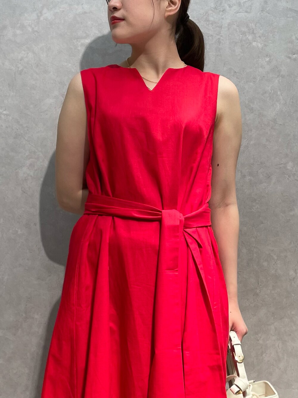 レッド系のワンピース、ホワイト系のショルダーバッグ、ベージュ系のサンダルを着用したレディースの夏コーディネートの3枚目の写真