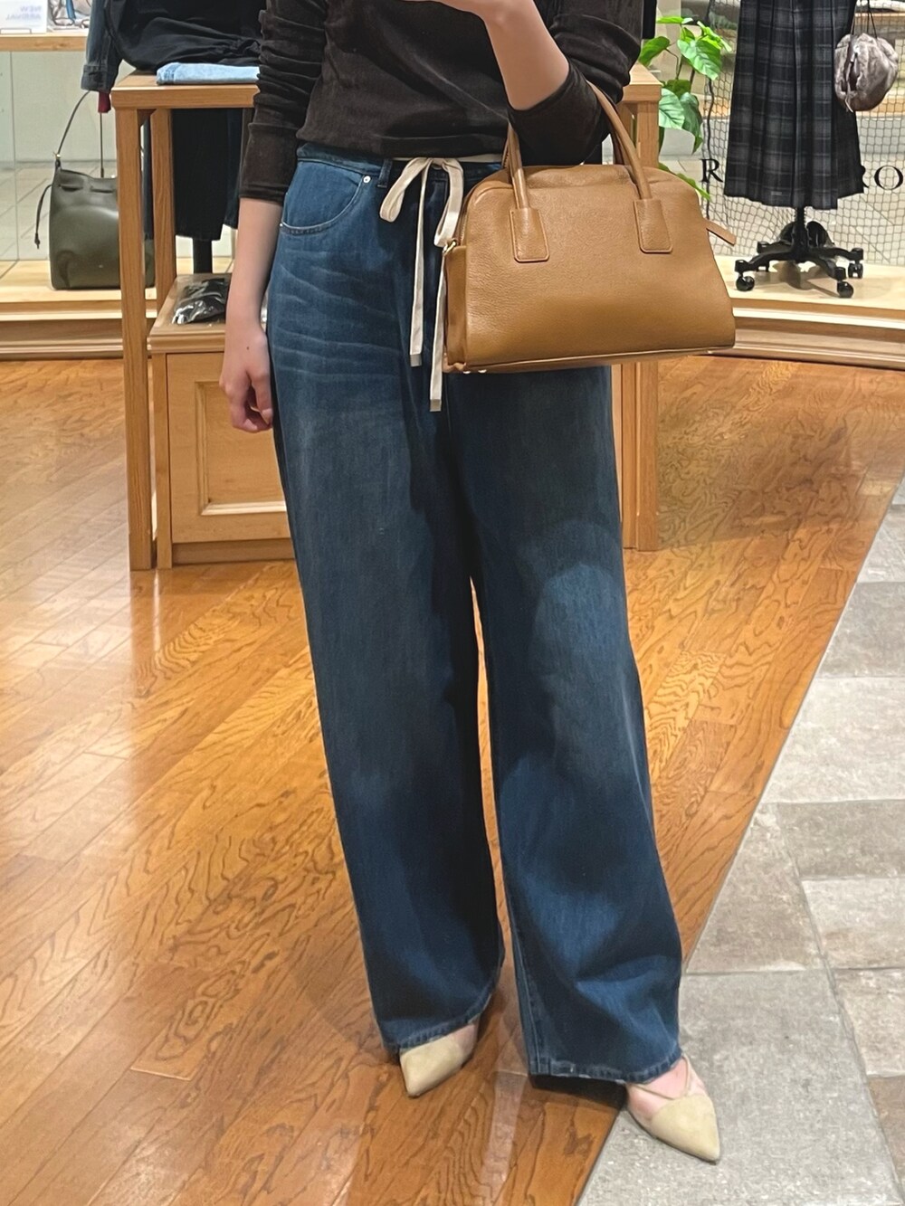 ブルー系のデニムパンツ、ベージュ系のパンプス、イエロー系のボストンバッグを着用したレディースの夏コーディネートの3枚目の写真