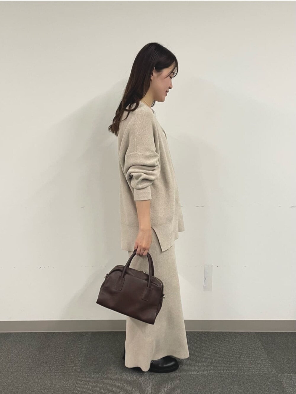 ホワイト系のニット/セーター、ブラック系のブーツ、ホワイト系のスカートを着用したレディースの秋コーディネートの3枚目の写真