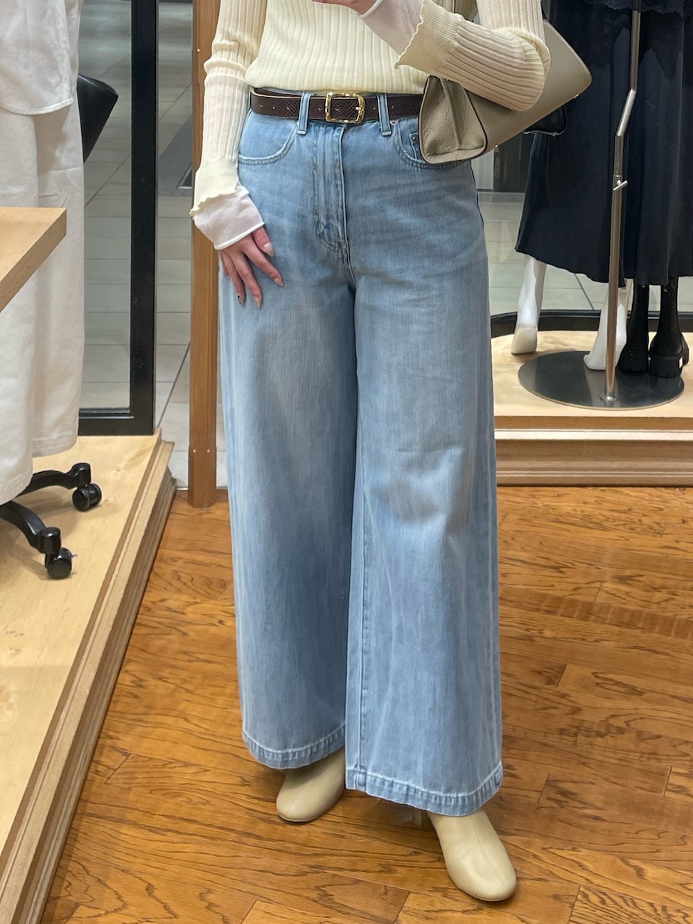 ブルー系のデニムパンツ、イエロー系のニット/セーター、ベージュ系のハンドバッグを着用したレディースの冬コーディネートの3枚目の写真