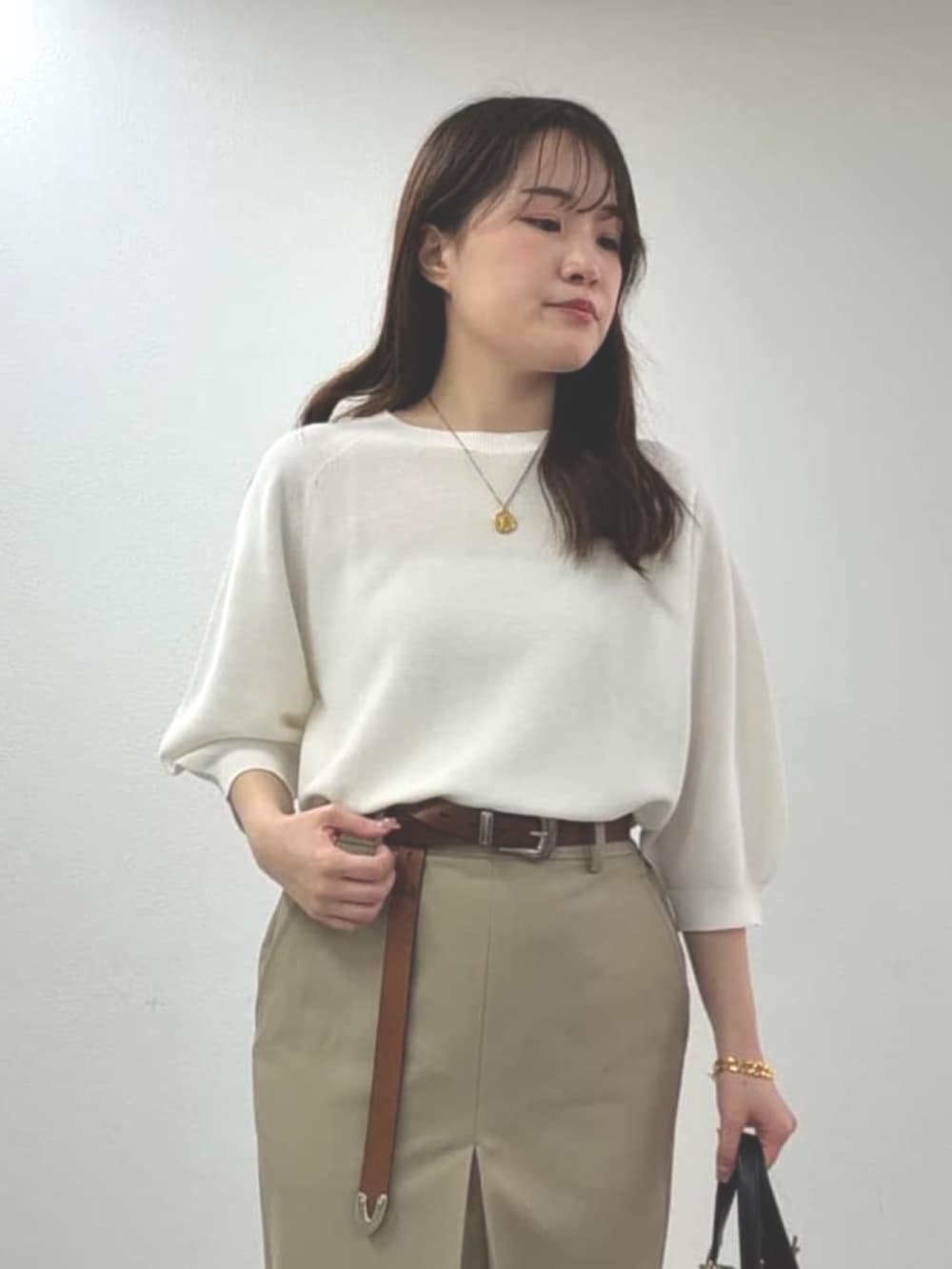 ブラウン系のサンダル、ベージュ系のスカート、ブラック系のハンドバッグを着用したレディースの春コーディネートの2枚目の写真