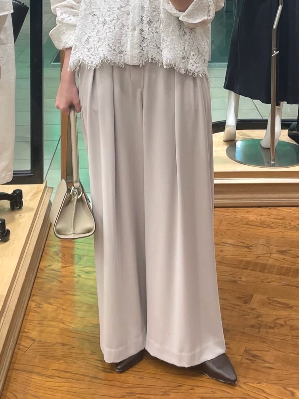 ホワイト系のシャツ/ブラウス、グレー系のスラックス、ベージュ系のハンドバッグを着用したレディースの冬コーディネートの3枚目の写真