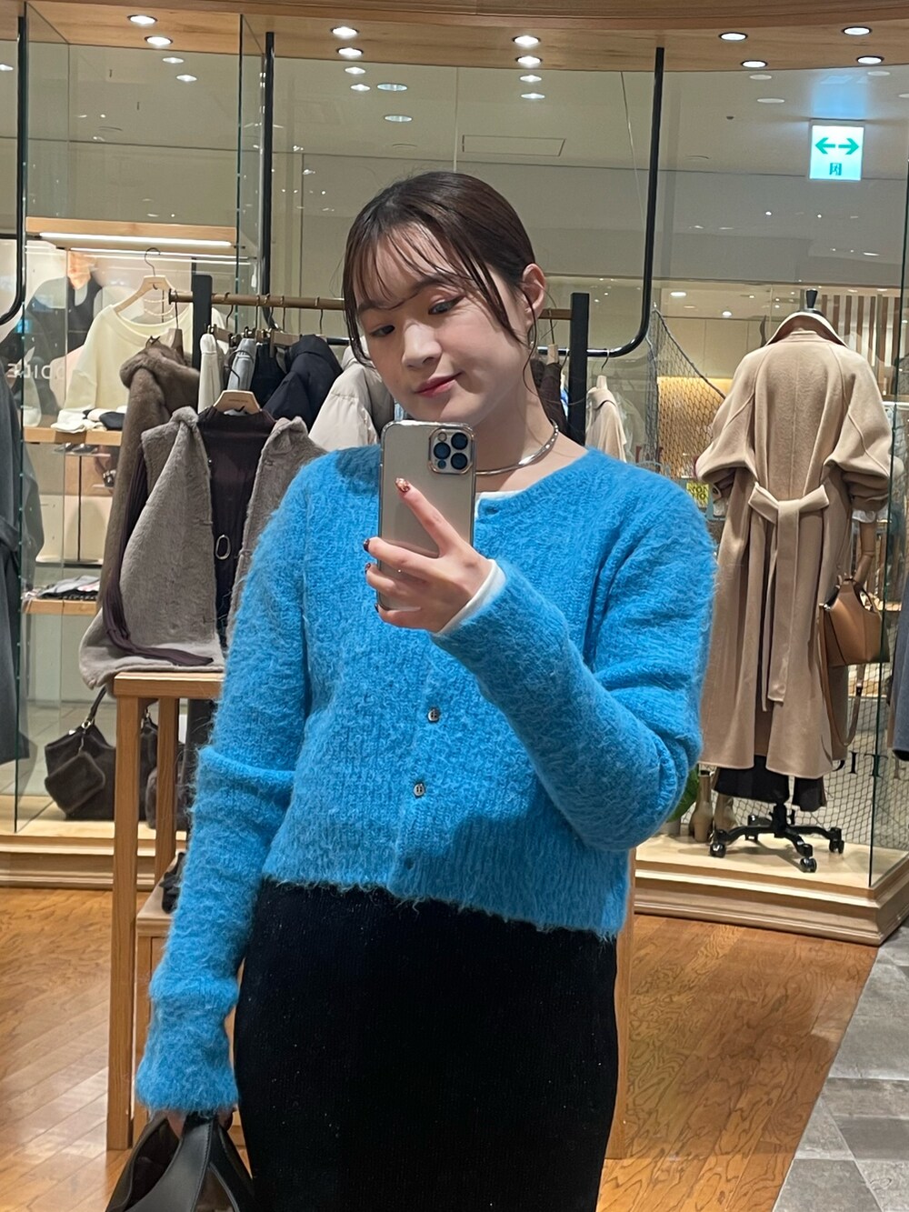 ブラック系のスカート、ブラック系のハンドバッグ、ブルー系のカーディガン/ボレロを着用したレディースの秋コーディネートの2枚目の写真