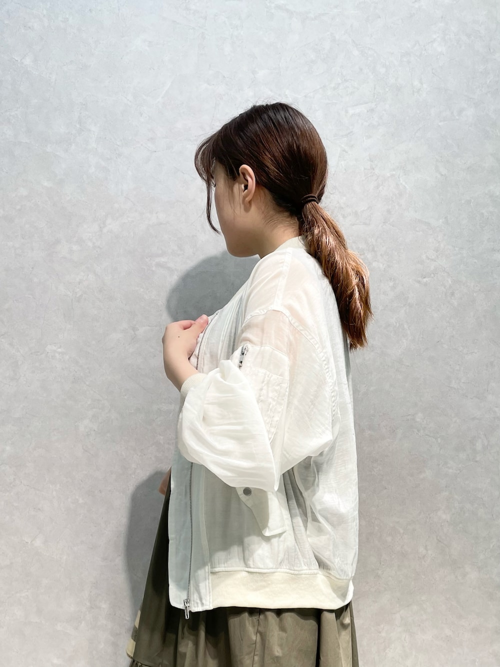 ホワイト系のミリタリージャケット、グリーン系のワンピースを着用したレディースの夏コーディネートの3枚目の写真