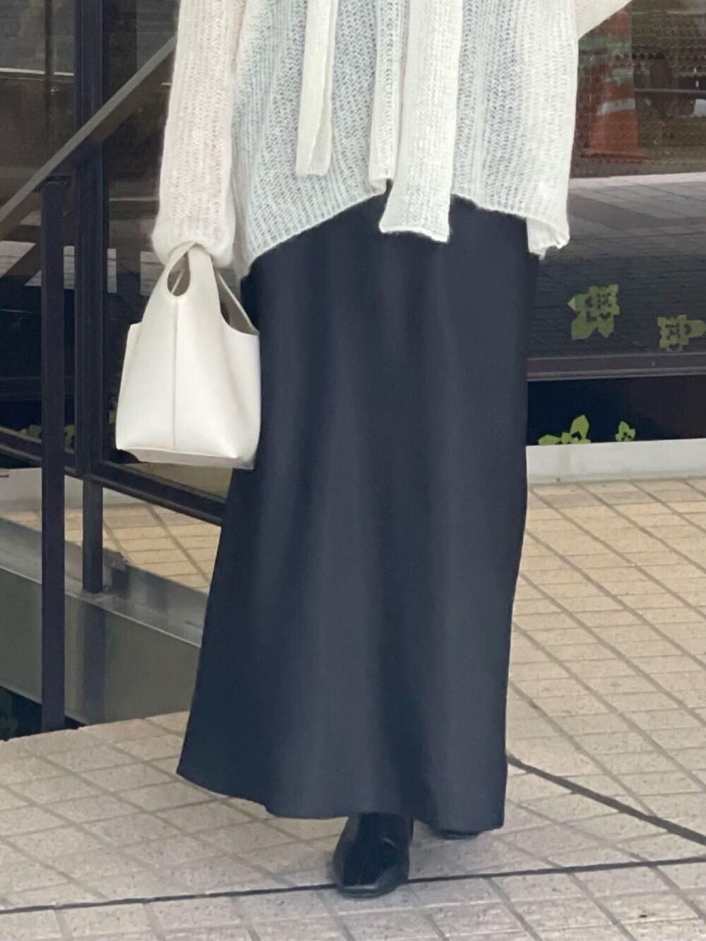 ホワイト系のニット/セーター、ブラック系のスカート、ブラック系のブーツを着用したレディースの秋コーディネートの4枚目の写真