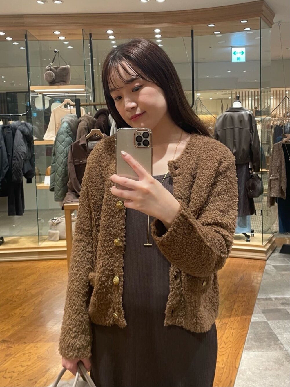 ブラウン系のカーディガン/ボレロ、ブラウン系のワンピース、ベージュ系のボストンバッグを着用したレディースの秋コーディネートの2枚目の写真