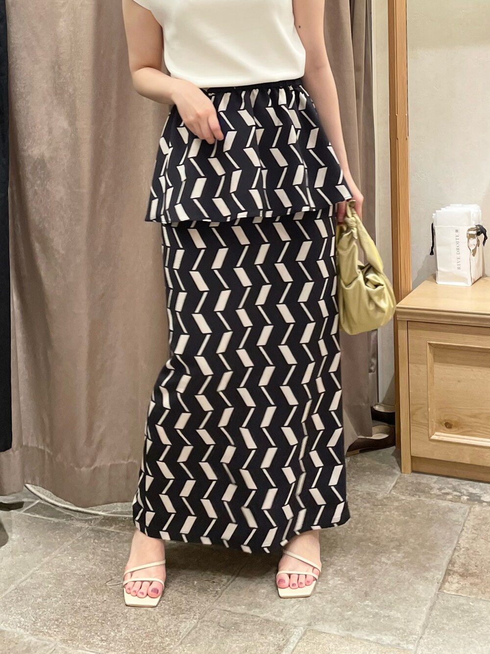 ホワイト系のニット/セーター、ブラック系のスカート、グリーン系のハンドバッグを着用したレディースの夏コーディネートの3枚目の写真